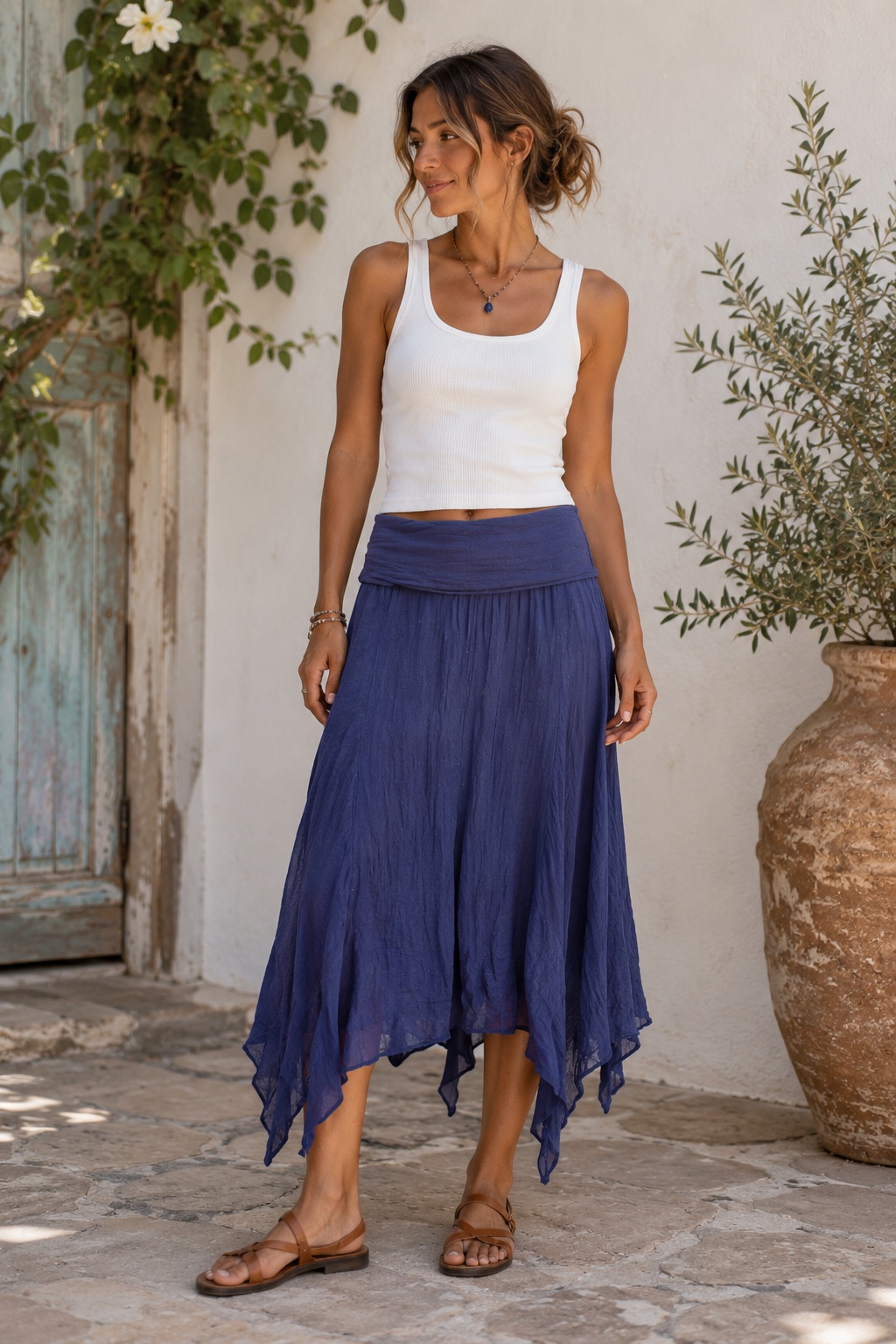 Model wearing a navy blue asymmetrical scarf skirt with a white tank top on a sunlit patio