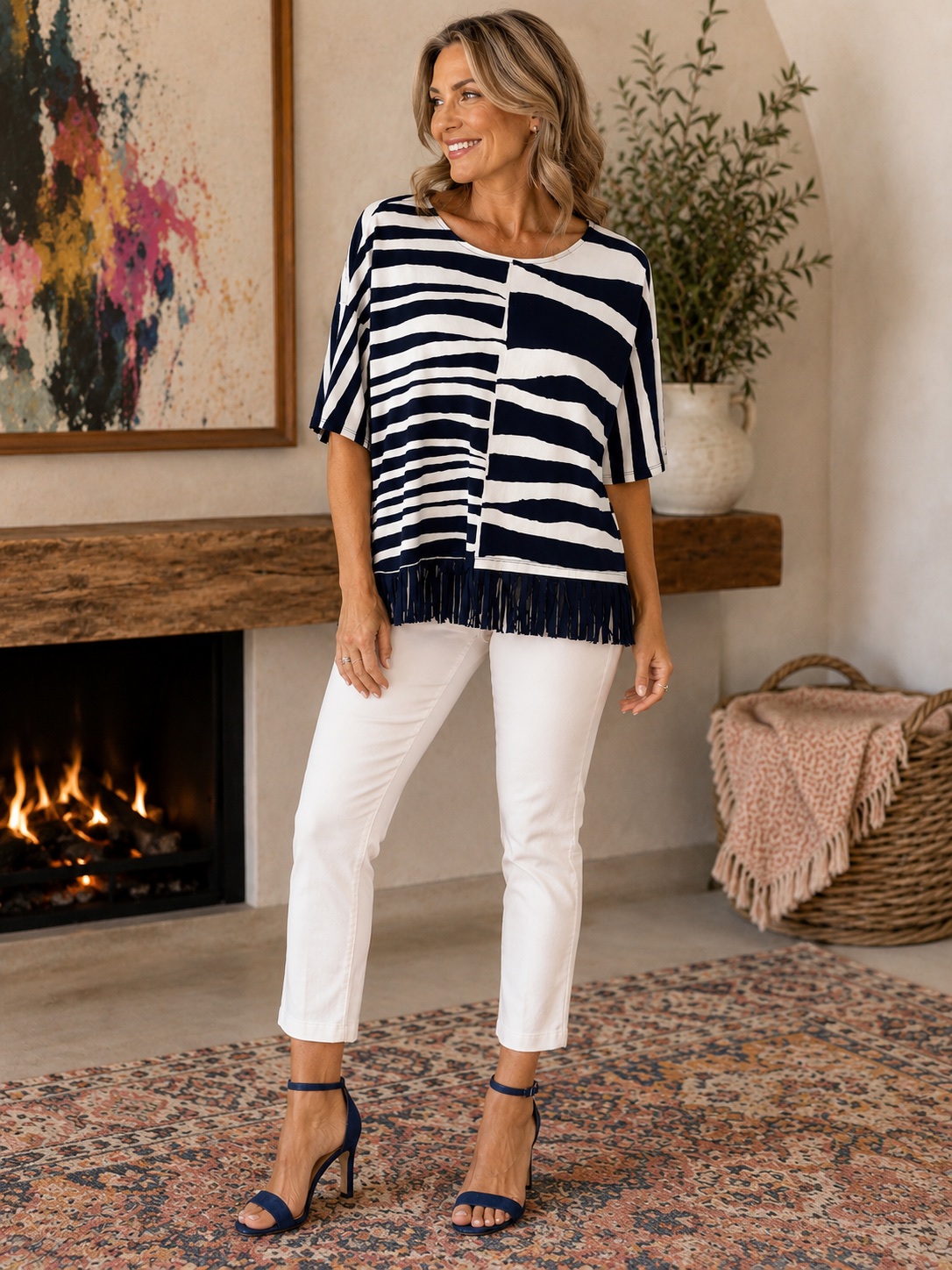 Model wearing a navy and white striped fringe-hem top with white pants